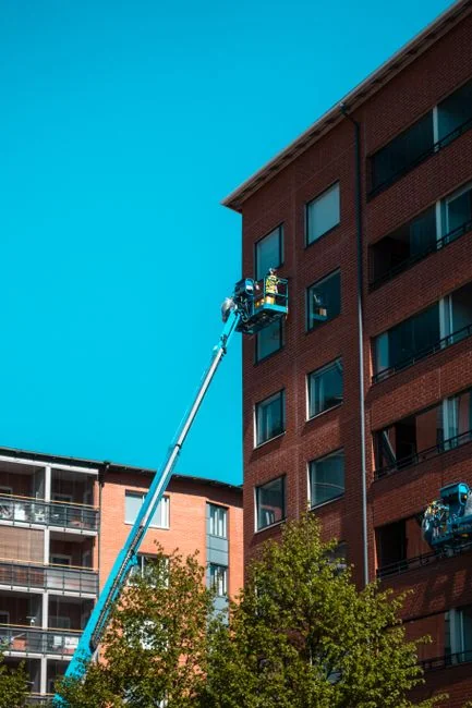 Two workers suspended while cleaning windows on a modern skyscraper facade.